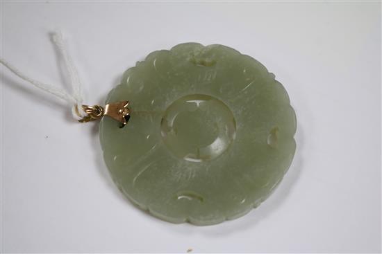 A gold mounted circular carved jade pendant, 2in.